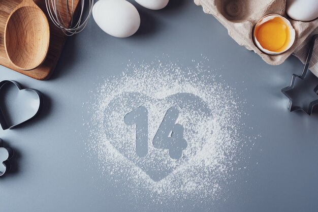 Números 14 y un corazón de harina. el concepto de san valentín. hacer galletas caseras para el día de san valentín, vista superior, endecha plana. ingredientes para hornear sobre un fondo gris.