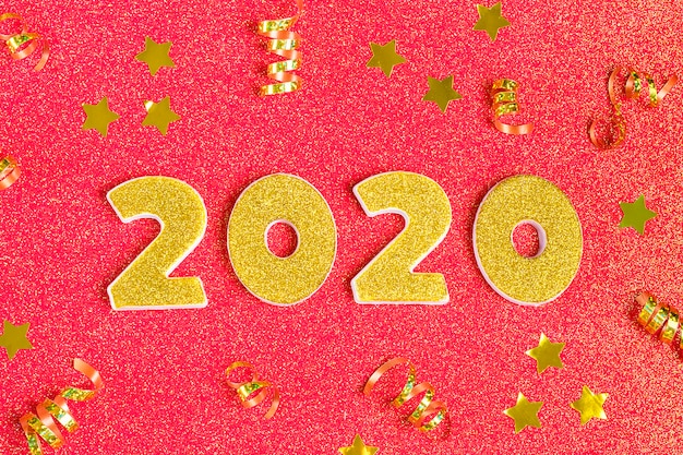 Números 2020 decorados con lentejuelas doradas, estrellas, cinta, bola en rojo coral brillante.