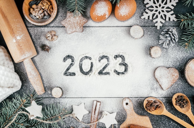 Números 2023 escritos em farinha com galhos de acessórios e ingredientes de cozimento de árvores de Natal Feliz Ano Novo 2023