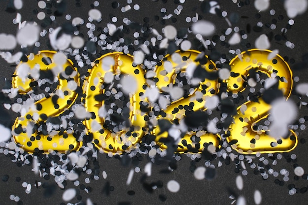 Foto números de balões de folha de ano novo em fundo preto confete preto e branco de natal de ano novo