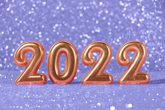 Números dorados 2022 sobre el brillante fondo violeta de moda.