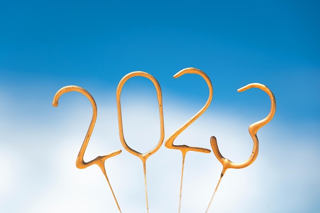 Foto números dorados para el próximo año nuevo 2023 contra el telón de fondo de un cielo soleado con nubes