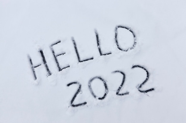 Números e a palavra olá são desenhados na neve no inverno, a inscrição sobre o ano novo de 2022