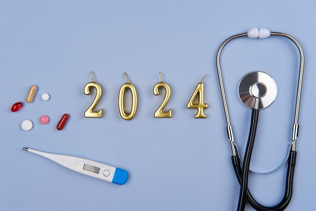 Números de estetoscopio 2024 y pastillas en fondo azul El concepto de atención médica y seguro en el nuevo año