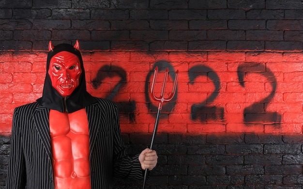 Números negros del diablo 2022 en una pared de ladrillo rojo