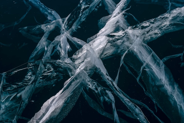 Numerosas rayas de grietas en el hielo transparente azul claro. Horizontalmente.