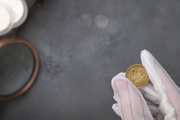 Numismática Monedas coleccionables antiguas de plata, oro y cobre sobre la mesa Un coleccionista con guantes especiales sostiene una moneda antigua Vista superior
