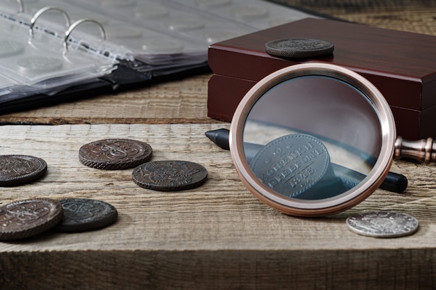 Numismatik. Alte Sammlermünzen auf einem Holztisch. Dunkler Hintergrund.