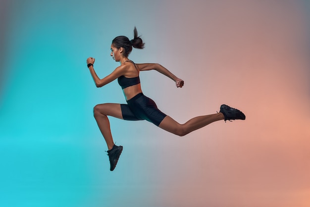 Nunca dejes de correr en toda su longitud de mujer joven atleta con cuerpo perfecto en ropa deportiva