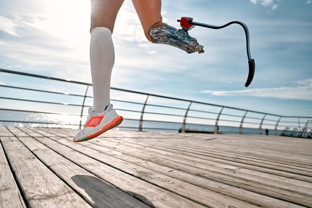 Nunca te rindas Foto recortada de una mujer discapacitada con pierna ortopédica en ropa deportiva saltando en el puente