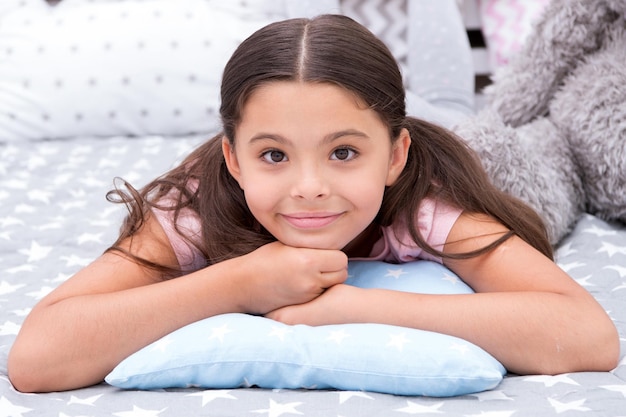 Nur entspannend Mädchen lag auf dem Kissen in ihrem Schlafzimmer Kind bereiten Sie sich darauf vor, ins Bett zu gehen Angenehme Zeit stilvolles Interieur Mädchen Kind lange Haare niedlichen Schlafanzug auf dem Kissen im Schlafzimmer entspannen Zeit zum Schlafen oder Nickerchen