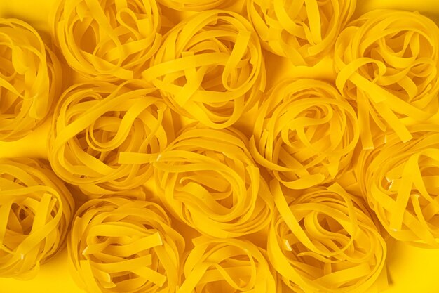 Nur wenige hausgemachte Fettuccine Nester isoliert auf gelbem Hintergrund