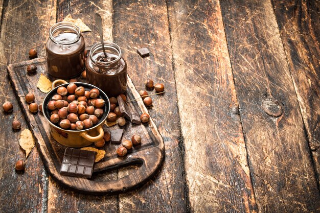 Nussbutter mit Schokolade und Haselnüssen auf hölzernem Hintergrund