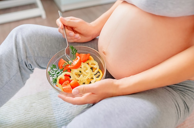 Foto nutrição saudável e gravidez. barriga de mulher grávida e salada de legumes