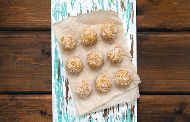 Foto nutrición para deportistas snack saludable. bolas de energía saludable caseras hechas de ingredientes naturales de avena seca, miel, frutos secos, nueces en coco sin azúcar sobre una tabla de cortar. vista desde arriba