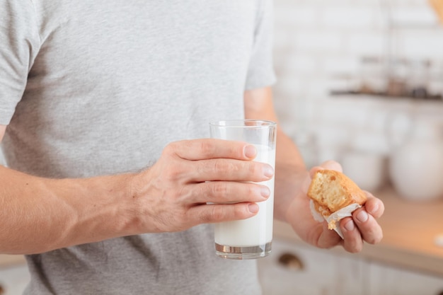 Nutrición deportiva Captura recortada de hombre comiendo muffin con leche de soja Desenfoque de fondo de cocina