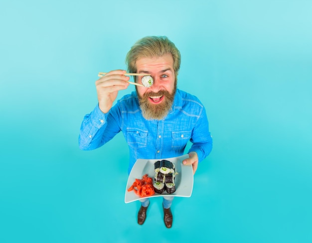 Nutrición exótica hombre de mariscos comer sushi hombre mantenga pieza sushiroll delante del ojo hombre con sushi en