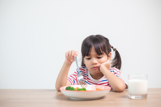 Nutrición hábitos alimenticios saludables para el concepto de los niños A los niños no les gusta comer verduras Niña linda se niega a comer verduras saludables