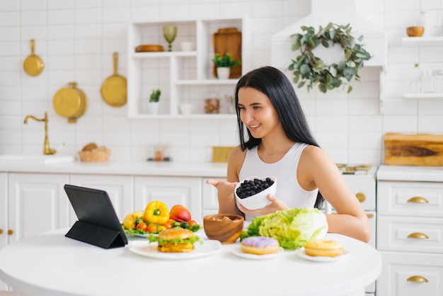 Nutricionista de mulher feliz realiza uma aula online ou conferência na cozinha sobre o tema alimentação saudável e perda de peso