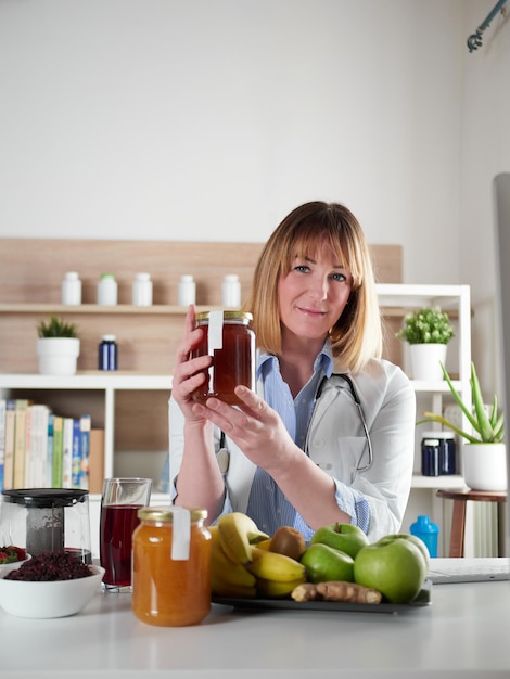 Nutricionista femenina sosteniendo miel en estudio de oficina