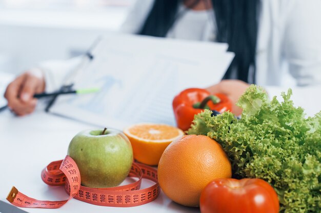 Nutricionista feminina de jaleco branco, sentado dentro de casa, no escritório no local de trabalho.