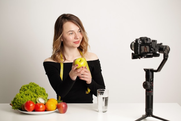 Nutricionista graba un video blog sobre alimentación saludable en un teléfono móvil.