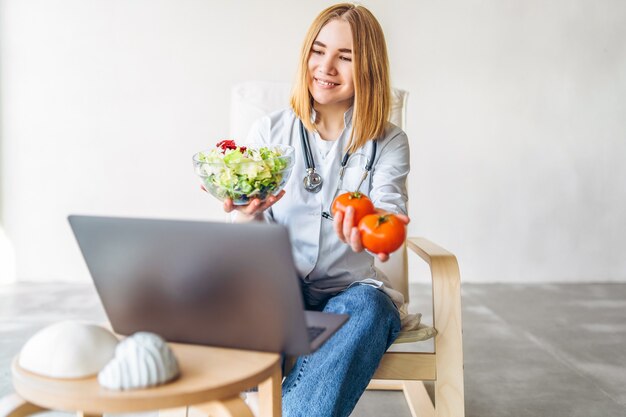 Nutricionista médica realiza consulta online com laptop.