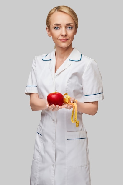nutricionista médico conceito de estilo de vida saudável - segurando maçã vermelha orgânica e fita métrica