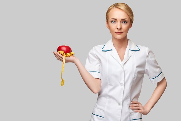 nutricionista médico conceito de estilo de vida saudável - segurando maçã vermelha orgânica e fita métrica