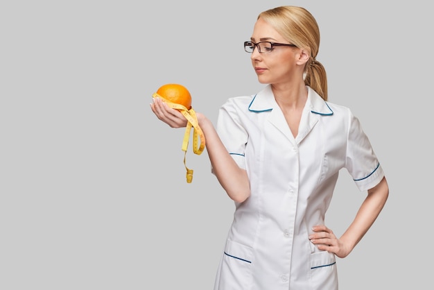 nutricionista médico conceito de estilo de vida saudável - segurando uma fruta laranja e fita métrica