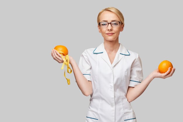 nutricionista médico conceito de estilo de vida saudável - segurando uma fruta laranja e fita métrica