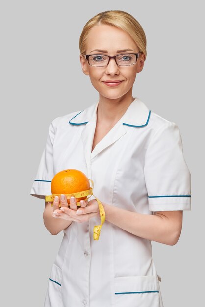 nutricionista médico conceito de estilo de vida saudável - segurando uma fruta laranja e fita métrica