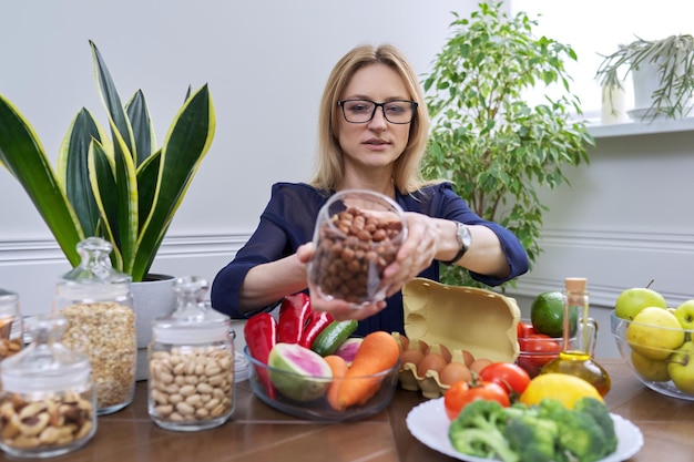 Nutricionista profissional de mulher de meia idade sentada à mesa com alimentos avelãs