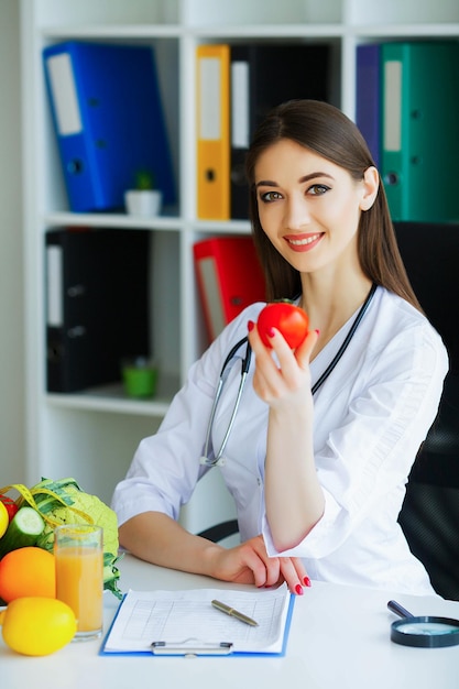 Nutricionista segurando um tomate nas mãos