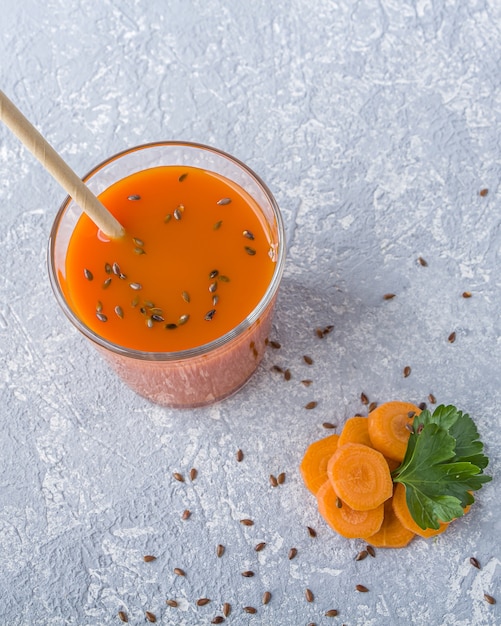 Nutritivo jugo de zanahoria detox en vaso con semillas de lino y hojas de perejil. Concepto de dieta alcalina. Bebida vegetariana ecológica
