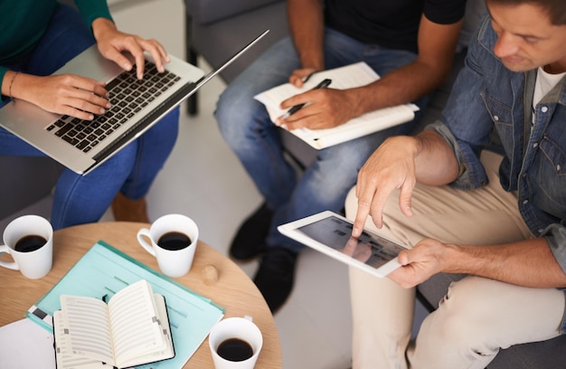 Nutzung von Technologie, um ihre Meetings effizienter zu gestalten Ein Team junger Geschäftsleute, die Technologie bei einem informellen Meeting einsetzen