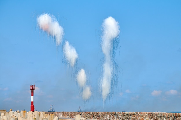 Nuvens brancas de fibra de carbono escondendo destruidores navais de mísseis anti-navio. Lançamento de antimísseis em tempo de show militar, fundo de céu azul. Navios de guerra em treinamento de combate, bombeiros no Mar Báltico