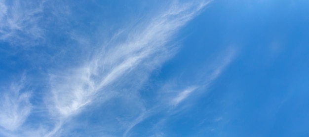 Nuvens cirros brancas naturais como penas estão diagonalmente no céu azul Skyscape Banner Copie o espaço