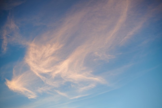 Nuvens de cirro finas Nuvens de cirro alaranjadas altas se expandindo pelo vento para cobrir o céu azul marinho profundo no pôr do sol