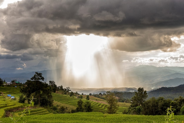 Nuvens de tempestade com chuva e raio de sol sobre a montanha