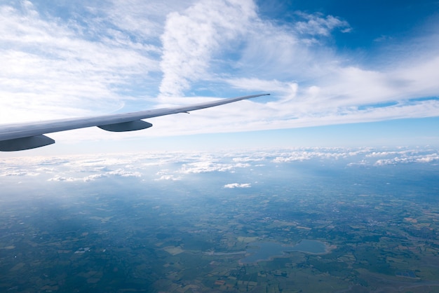 Nuvens e céu dia ensolarado através da janela do avião