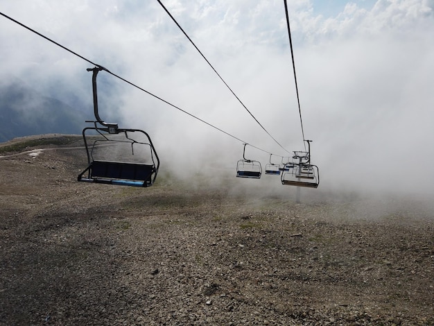 Nuvens envolvendo teleférico moderno com bancos em terreno montanhoso incrível