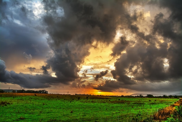 Nuvens escuras em um céu dramático sobre um campo verde ao pôr do sol