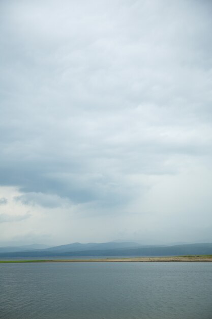 Nuvens negras com chuva nas montanhas e acima da água