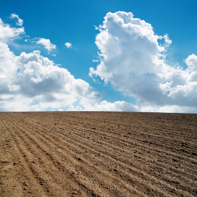 nuvens no céu azul e campo arado