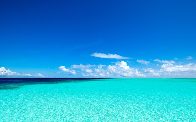 Nuvens no céu azul sobre mar calmo com reflexo da luz solar