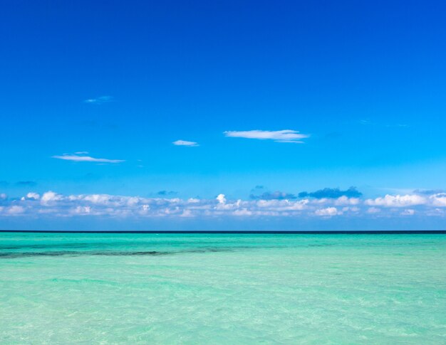 Nuvens no céu azul sobre o mar calmo com reflexo da luz do sol