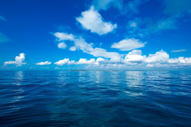 Nuvens no céu azul sobre o mar calmo com reflexo da luz do sol