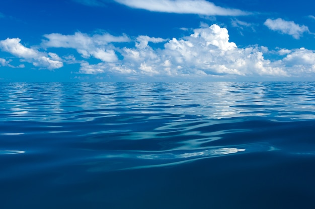 Nuvens no céu azul sobre o mar calmo com reflexo da luz do sol