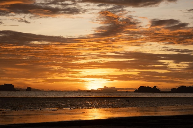 Nuvens no céu reflexo do sol na água e areia na praia